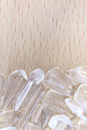 Clear quartz jewel heap on varnished light wood background. Pile mineral pebbles texture.の写真素材