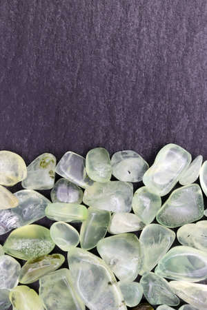 Prehnite heap jewel texture on half black stone background. Place for text.