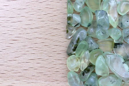 Prehnite jewel stone texture on light varnished wood background. Macro closeup.の写真素材