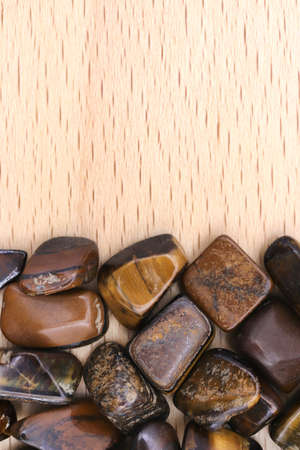 Tiger's Eye jewel texture in tweezers on light white isolated background. Macro closeup.