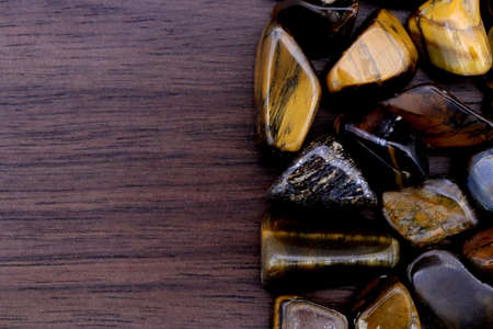 Tiger's Eye jewel texture on brown varnished wood background. Macro closeup.