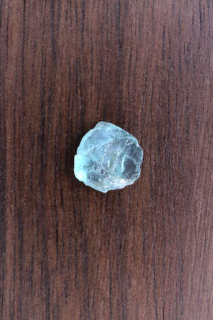 Apatite jewel stone texture on light varnished wood background. Macro closeup.