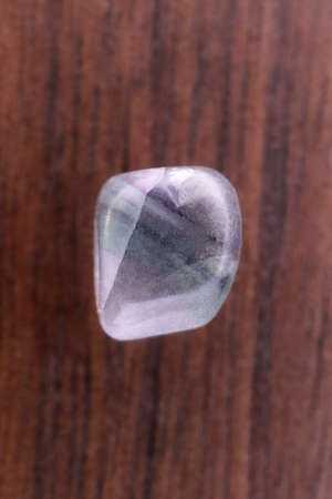 Fluorite jewel stone texture in tweezers on black background. Macro closeup.