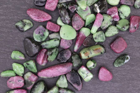 Ruby zoisite rare jewel stones texture on light varnished wood background.
