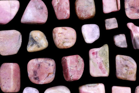 Rhodochrosite jewel stone texture in tweezers on black background. Macro closeup.の写真素材
