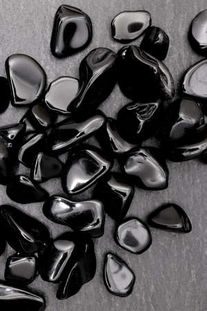 Obsidian heap jewel stones texture on half black background. Place for text.
