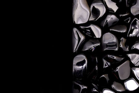 Obsidian heap jewel stones texture on half black background. Place for text.