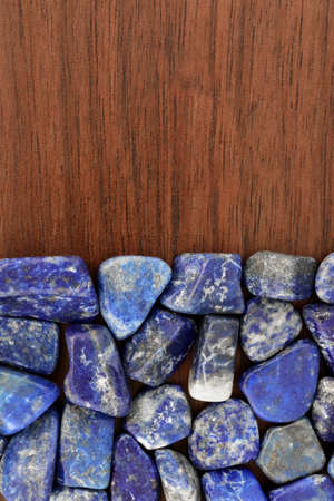 Lapis lazuli jewel stone texture on brown varnished wood background. Macro closeup.