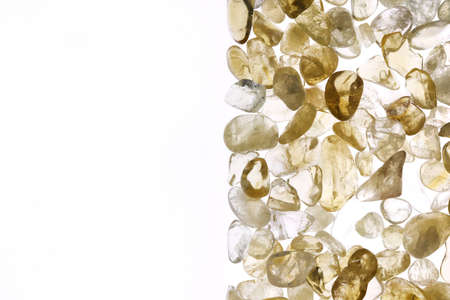 Citrine jewel stone texture in tweezers on white light isolated background. Macro closeup.の写真素材