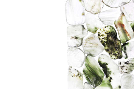 Green rutilated heap jewel stones texture on half white light isolated background. Place for text.