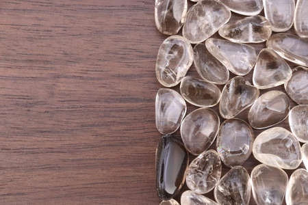 Smoky quartz jewel stone texture on brown varnished wood background. Macro closeup.の写真素材
