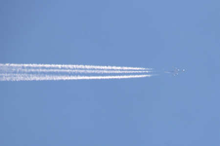 The plane flies to the right in the clear blue sky. Leaves a trail of smoke.