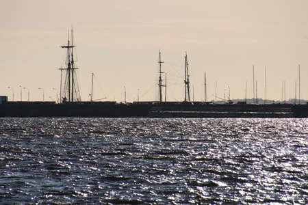 Silhouette of a sailing ship against the background of port piers on the shores of the Gulf of...
