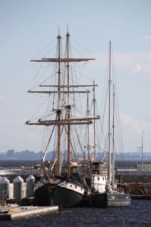 Two sailing ships are moored to each other at the pier.