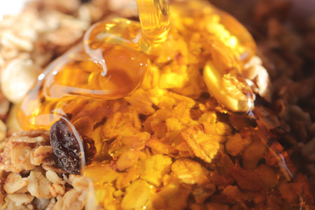Juicy honey pours on muesli. Delicious healthy breakfast. macro closeup.