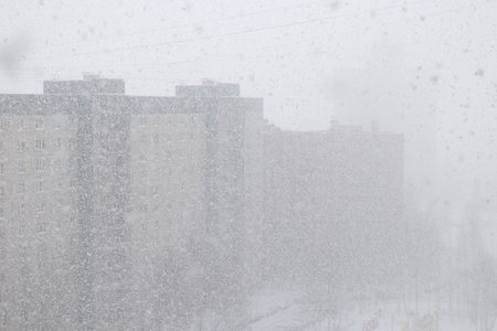 Winter snowfall against the background of a multi-storey residential building in a residential areaの写真素材
