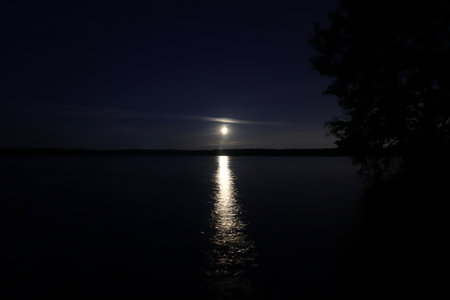 The moon above the surface of the night lake. Long Exposure.の写真素材