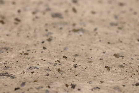 Close-up of textured beige paper texture surface with scattered dark specks.の写真素材