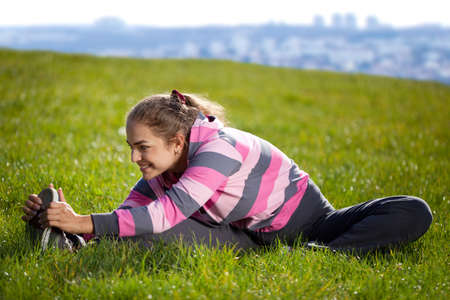 Young Beautiful Woman Doing Exercises on the Grass in the City Parkの写真素材