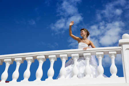 Happy smiling bride standing on the terrace and greeting somebodyの写真素材