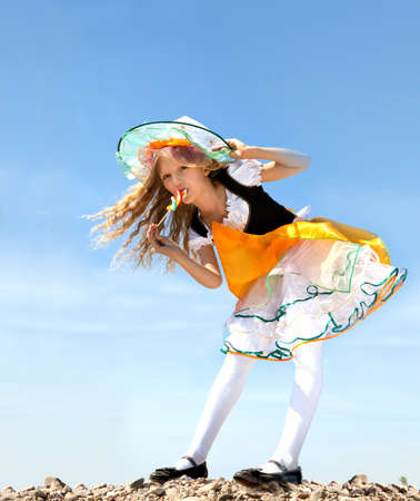 Cute Emotional Little Girl in a Costume of Witch Licking a Colorful Candy at the Blue Sky.