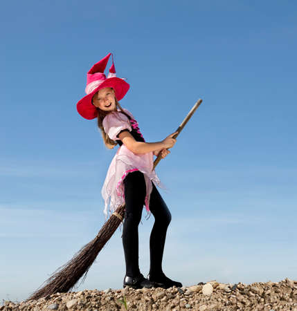 little beautiful witch with Jack O' Lantern peeking through a hole in white paperの写真素材