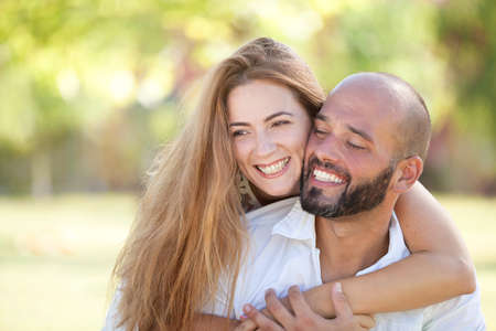 Smiling Young Woman and Young Man are Happy Together - they are Smiling and Embracing in Nature at the Bright Sunny Dayの写真素材