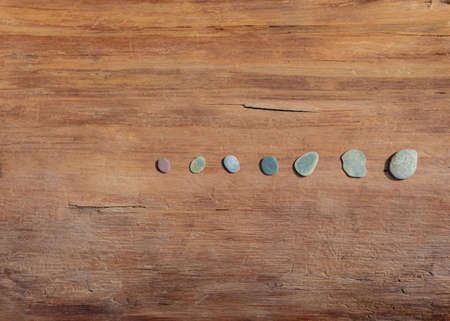 small flat rocks on the wooden beamの写真素材