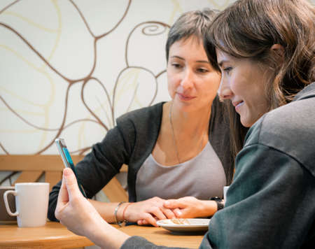 11 October 2020, Novosibirsk, Russia, two ledies look at smartphoneのeditorial素材