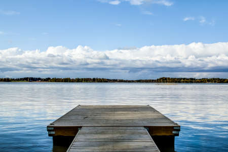 Pier under low clouds on a bright blue lakeの写真素材