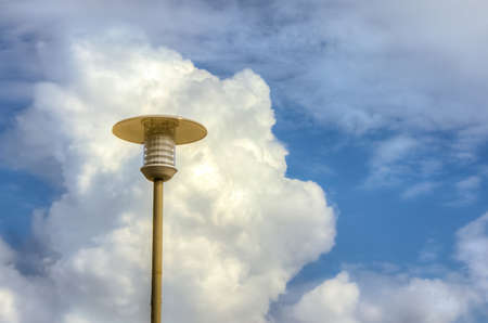 Lamppost against the fluffy white cloud and blue skiesの写真素材