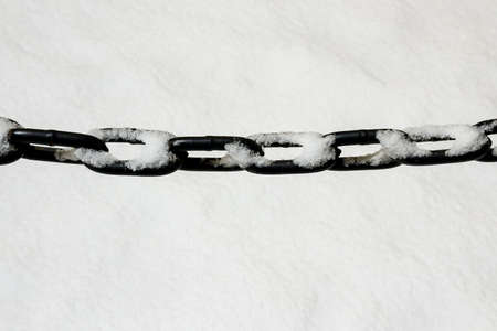 Metal chain hanging over white snowの写真素材