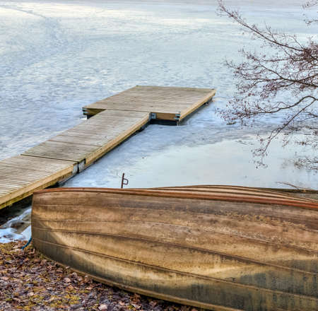 Old wooden rowboat and a pier in the frozen lakeの写真素材