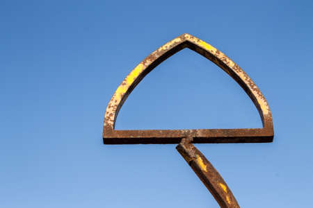 Old rusty triangle-shaped metal frame against blue skyの写真素材