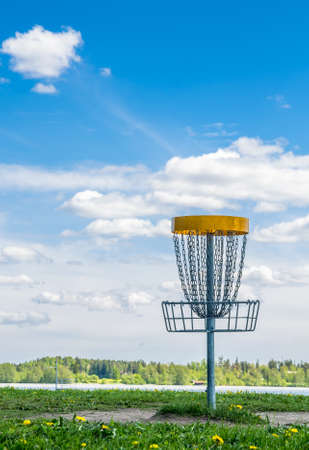 Frisbee golf basket on the grass against beautiful cloudy sky