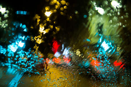 Blurred traffic lights in a wet car windshieldの写真素材