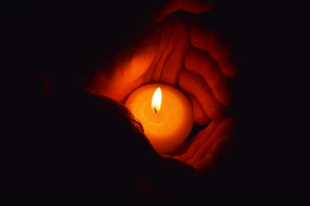 candle in hands on a black backgroundの写真素材