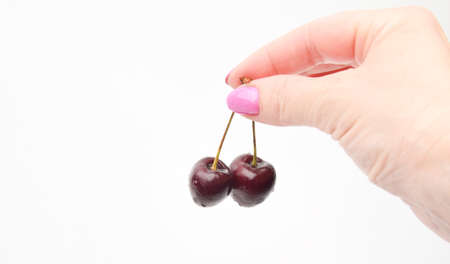 female hand holding two cherries on backgroundの写真素材