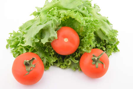 green salad and three tomatoes on a white plateの写真素材