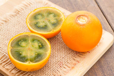Fruits and slices of lulo or naranjilla on the wooden table - Solanum quitoenseの写真素材