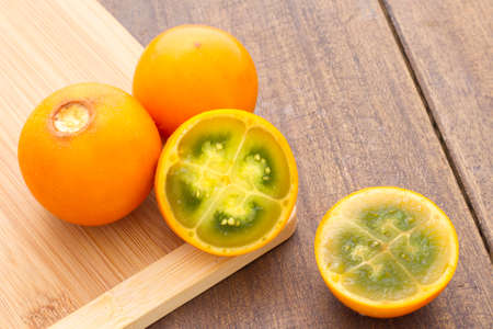 Fruits and slices of lulo or naranjilla on the wooden table - Solanum quitoenseの写真素材