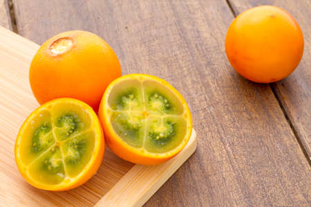Fruits and slices of lulo or naranjilla on the wooden table - Solanum quitoenseの写真素材