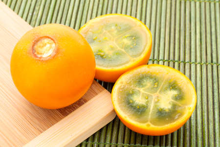 Fruits and slices of lulo or naranjilla on the wooden table - Solanum quitoenseの写真素材