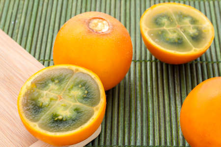 Fruits and slices of lulo or naranjilla on the wooden table - Solanum quitoenseの写真素材