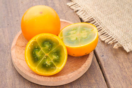 Fruits and slices of lulo or naranjilla on the wooden table - Solanum quitoenseの写真素材