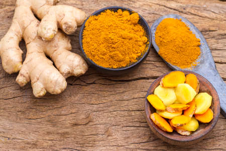 powder and roots of turmeric on wood - curcuma longa