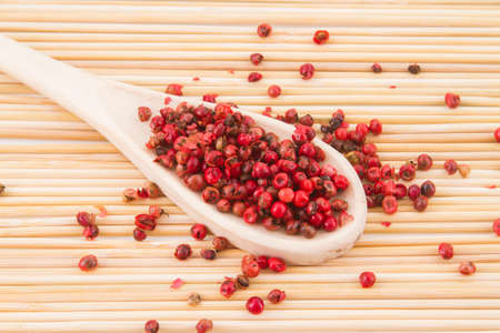 red peppercorns, on chopping board.