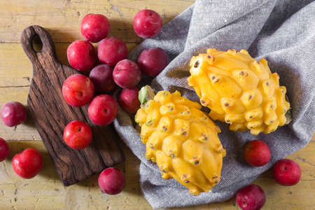 yellow pitahaya or dragon fruit and red plum on wooden backgroundの写真素材