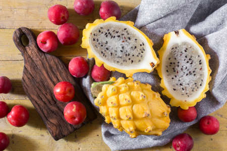 yellow pitahaya or dragon fruit and red plum on wooden backgroundの写真素材