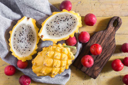 yellow pitahaya or dragon fruit and red plum on wooden backgroundの写真素材